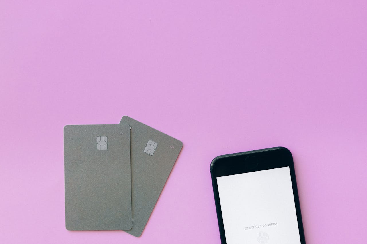 services-05 Flat lay of credit cards and smartphone on pink surface, symbolizing digital payment solutions.